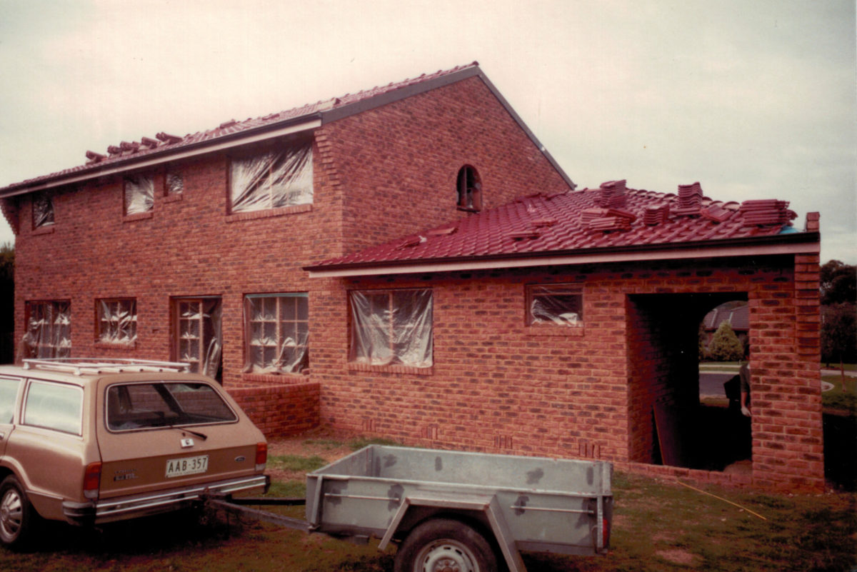 Ford Cortina with trailer parked in front of a house still in construction